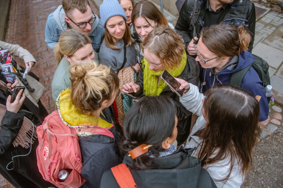 Ihmisiä kokoontuneena yhteen katsomaan älypuhelimen näyttöä