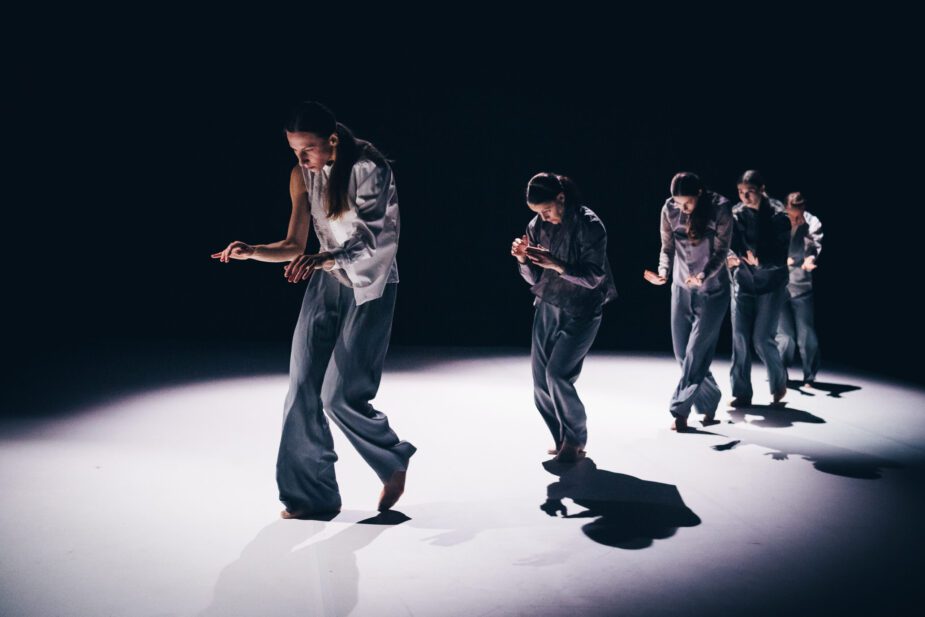 Nykytanssijoita askeltamassa jonossa näyttämön poikki.