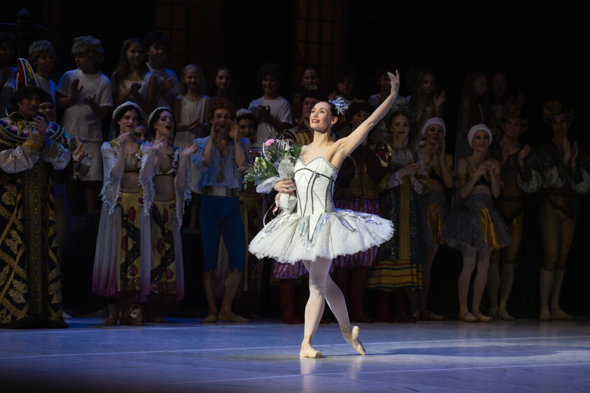 Balettitanssija ottaa aplodeja vastaan valkoisessa tutussaan.