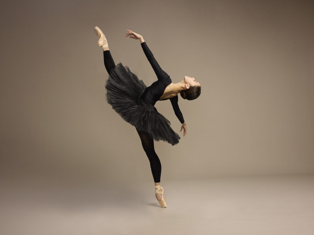 Mustapukuinen balettitanssija näyttävässä asennossa.